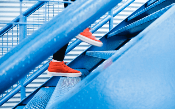 Shot of legs wearing red shoes climbing open tread industrial stairs