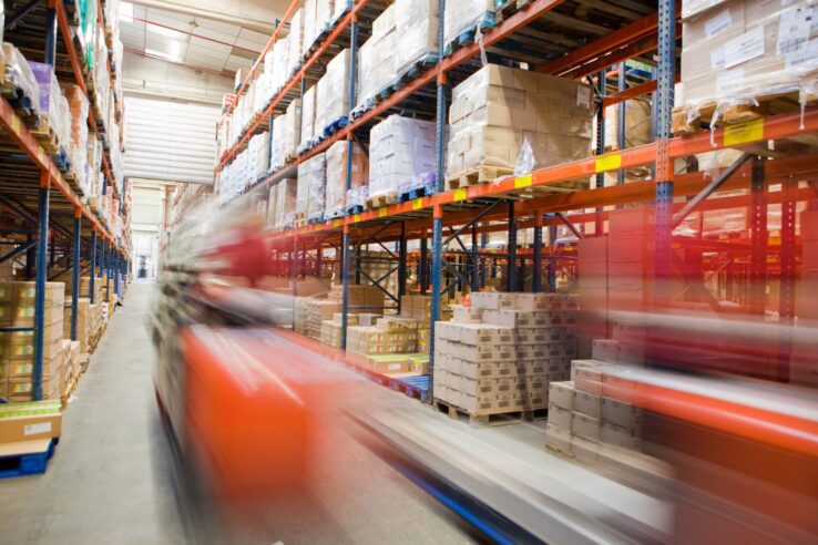 Blurred image of a red forklift in a warehouse aisle