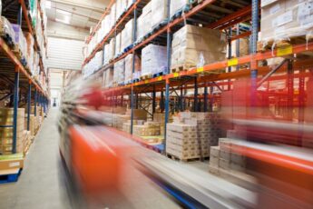 Blurred image of a red forklift in a warehouse aisle