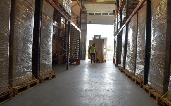 Worker pulling pallet into warehouse aisle