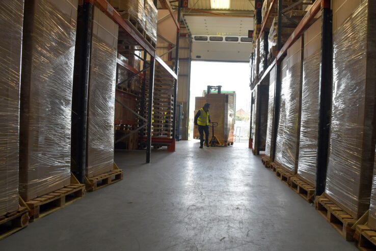 Worker pulling pallet into warehouse aisle
